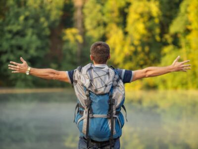 A man stood in nature arms stretched as he enjoys the mental helath boost of walking. The Outdoor Guide encourages outdoor activity to increase wellbeing.